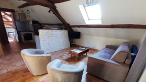 A cozy living room with a stone wall, a wooden ceiling, and a tiled floor.