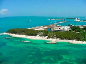 An aerial view of a coastal area with clear turquoise waters, a sandy beach, and a small island with buildings and docks. - Big Groups Welcome • Pool • Near Duval (Key West)