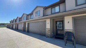 A row of townhouses with numbered garage doors, a clear sky, and a single chair outside.