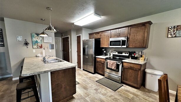 A modern kitchen with wooden cabinets, stainless steel appliances, and a marble countertop.