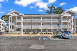 Un hôtel à plusieurs étages doté d’une cour intérieure, de balcons et d’un parking.