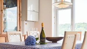 Una mesa de comedor con mantel de estampado geométrico, una botella de Prosecco, una hortensia azul y un cuenco de madera.