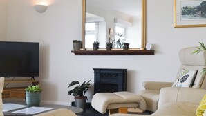 Una sala de estar con un espejo grande, una chimenea, un televisor y dos sofás.