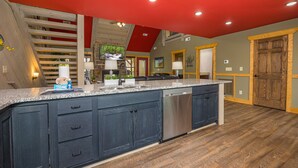 A kitchen with dark blue cabinets, a stainless steel dishwasher, and a red ceiling. - Smoky Mountain Plunge (Gatlinburg)