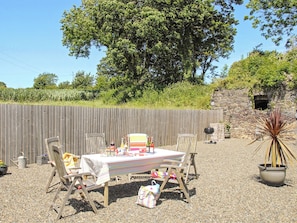 An outdoor dining area with a table set for four, surrounded by wooden chairs.