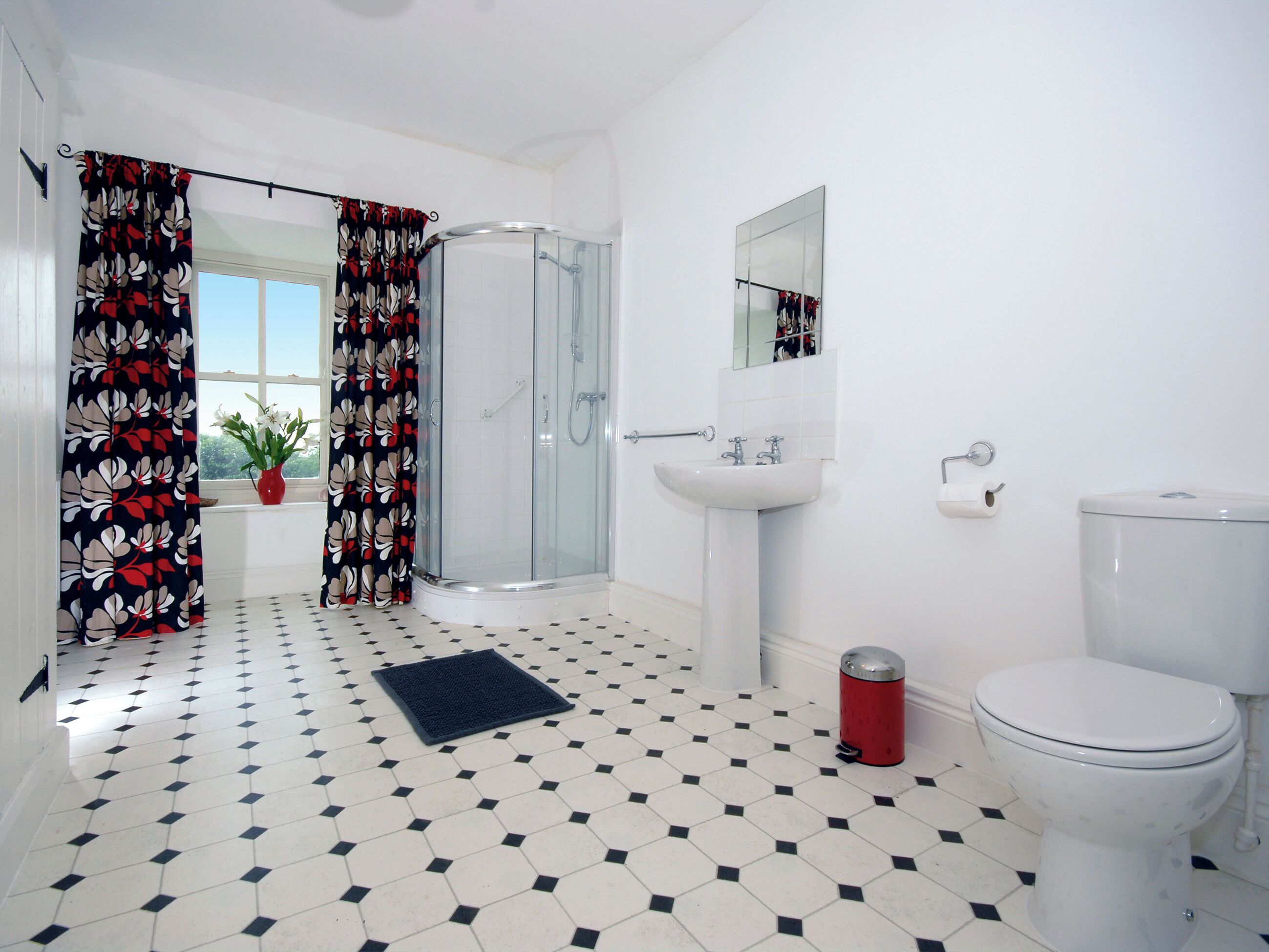 Ein Badezimmer mit Dusche, Toilette, Waschbecken und Spiegel.