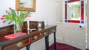 Een houten consoletafel met een spiegel, een vaas tulpen en een rood boek.