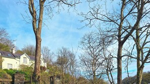 Un portón de piedra que da a una casa de fachada clara y tejado inclinado.
