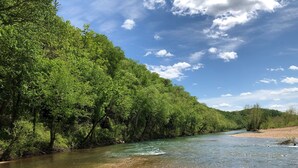 A river flowing through a forested area with clear water and sandy banks.
