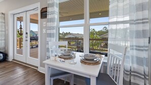 Un coin repas avec une table dressée pour deux personnes, une vue sur le jardin et un panneau indiquant la présence d’une connexion Wi-Fi.