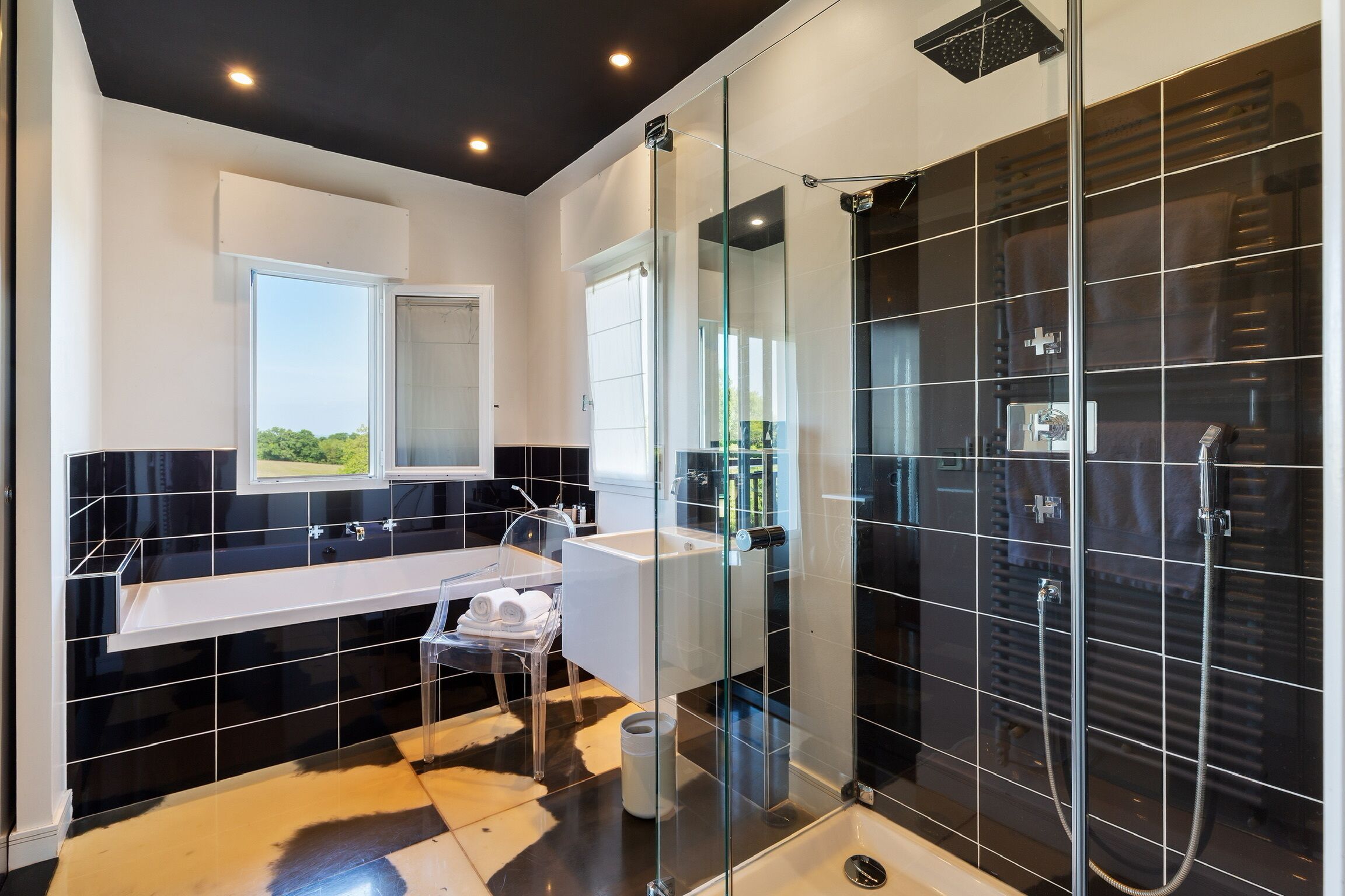 Une salle de bain moderne avec une douche à parois de verre, un lavabo blanc et un grand miroir.