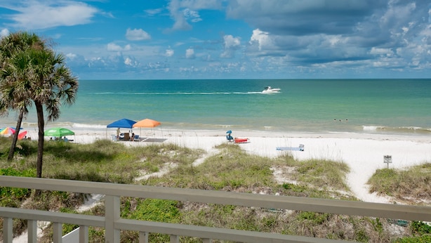 A beach with umbrellas, a boat, and a sign. - Amazing View, Updated Beachfront Condo (Bradenton Beach)