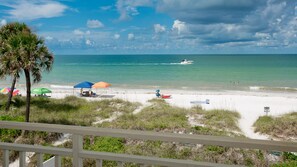 Une plage avec des parasols, un bateau et un panneau.