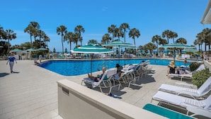 A pool area with lounge chairs and umbrellas, surrounded by palm trees. - Updated Beachfront Condo at Prestigious Long Boat Key Resort (Longboat Key)