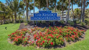 A sign for The Resort Longboat Key Club with a garden of red flowers in front. - Updated Beachfront Condo at Prestigious Long Boat Key Resort (Longboat Key)