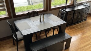 Uma sala de jantar com uma mesa retangular, quatro cadeiras, um banco e um armário.