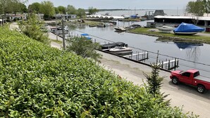 Uma marina com barcos atracados, uma área coberta e uma caminhonete vermelha estacionada perto da água.