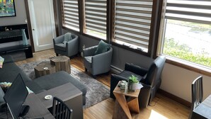 Uma sala de estar moderna com um sofá, poltronas, uma mesa de centro e uma televisão.