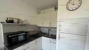 Une cuisine de taille réduite équipée d’un four à micro-ondes, d’une cuisinière, d’un évier et d’armoires blanches.