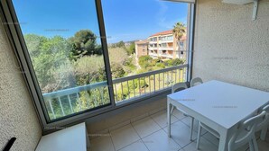 Un balcon avec une table et des chaises blanches, une vue sur un quartier résidentiel et un ciel dégagé.