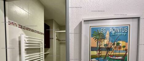 Une salle de bain avec un radiateur blanc, des toilettes et une affiche encadrée représentant « Les Pointus Sanary ».