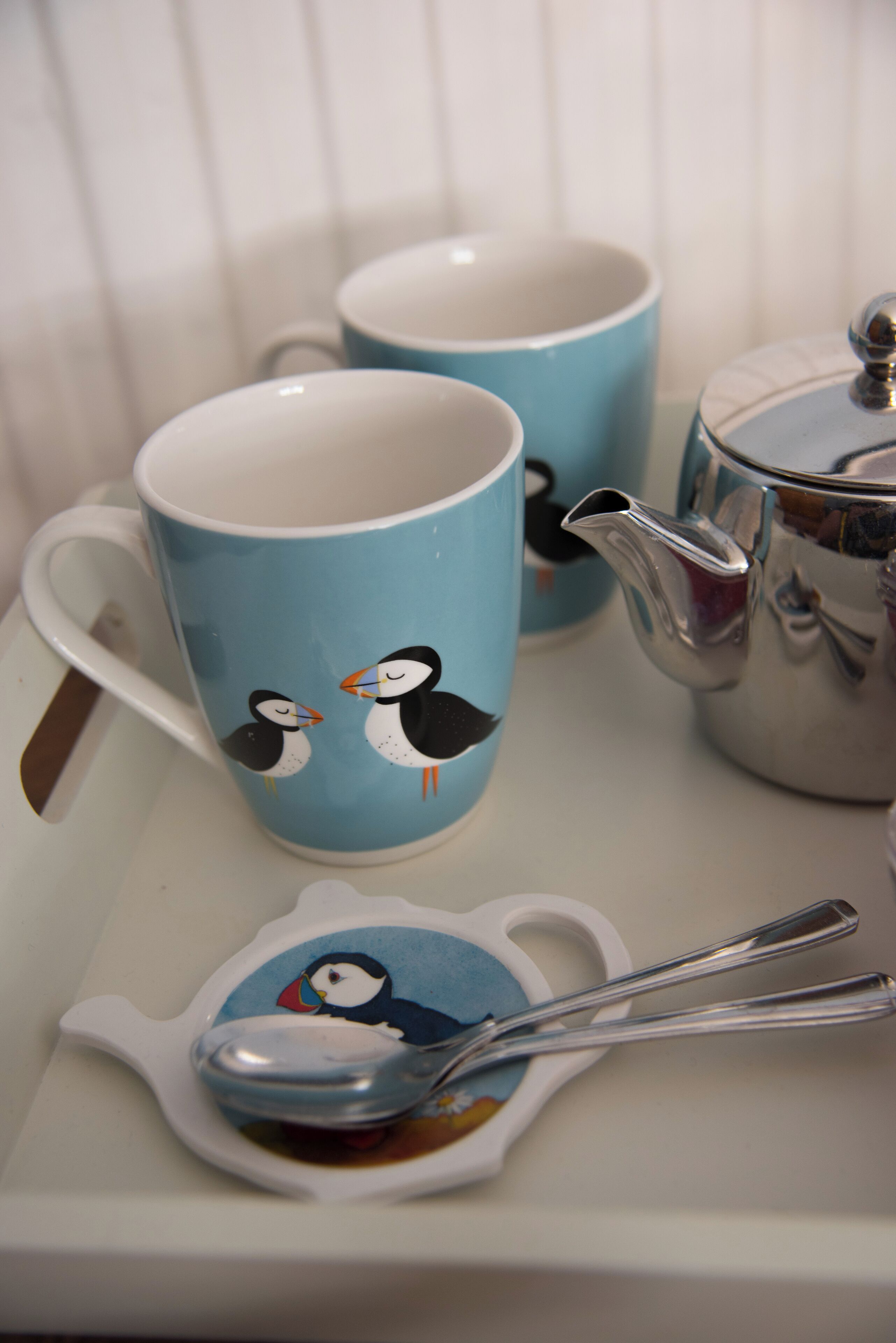 A tray with two mugs and a teapot, each featuring a penguin design.