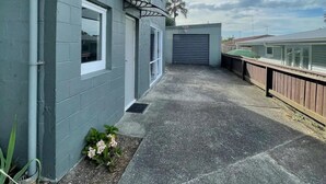 Ein Wohngebäude mit grauem Anstrich, einer Beton-Terrasse und einem Holzzaun.