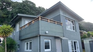 Ein zweistöckiges Haus mit Balkon, Garage und einem kleinen Garten.