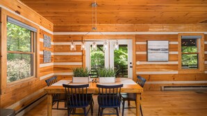 A wooden cabin interior with a dining table, four chairs, and a view of greenery outside. - Private, Peaceful Log Cabin w/ wrap around porch and fireplace. Central location (Boone)