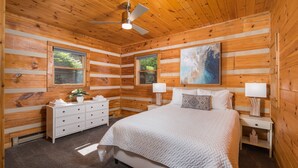A wooden cabin bedroom with a bed, dresser, and two nightstands. - Private, Peaceful Log Cabin w/ wrap around porch and fireplace. Central location (Boone)
