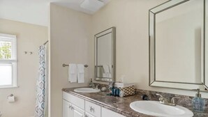 A bathroom with two sinks, a large mirror, and a shower curtain. - Sea Shell Room — Bright Coastal Luxury with Extra Space to Unwind (Rehoboth Beach)