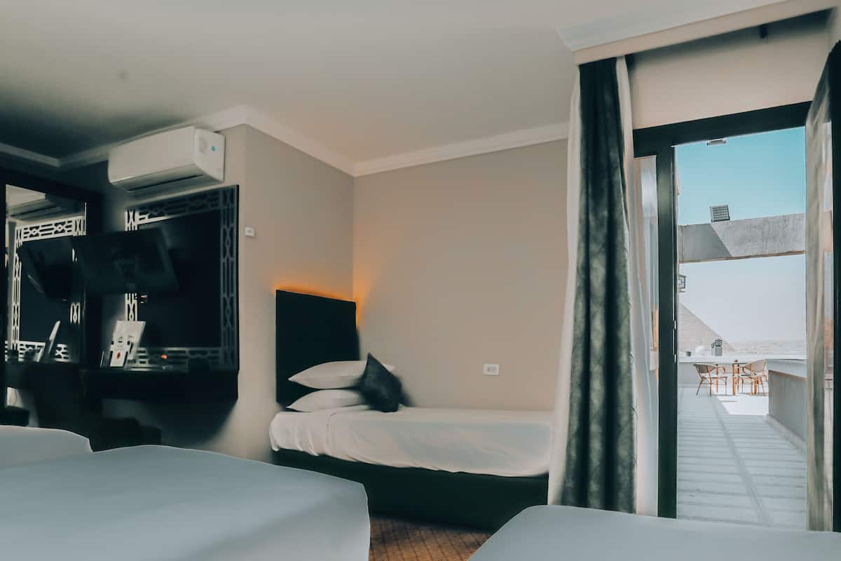 A hotel room with two beds, a large window, and a view of the outside.