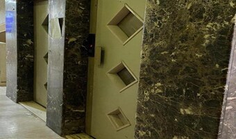Un pasillo con paredes de mármol y recortes geométricos.