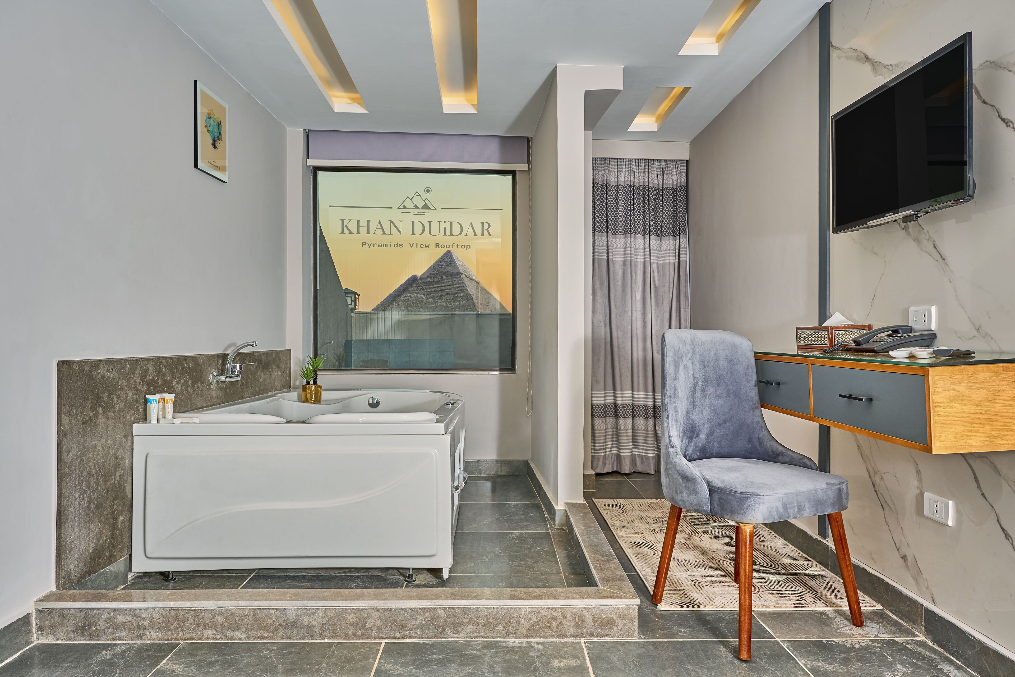 A modern bathroom with a bathtub, a vanity with a mirror, and a television mounted on the wall.