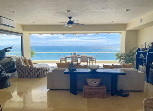 Enjoy ocean views from the large window in this stylish living room, featuring a dining table, sofa, and comfortable seating area.