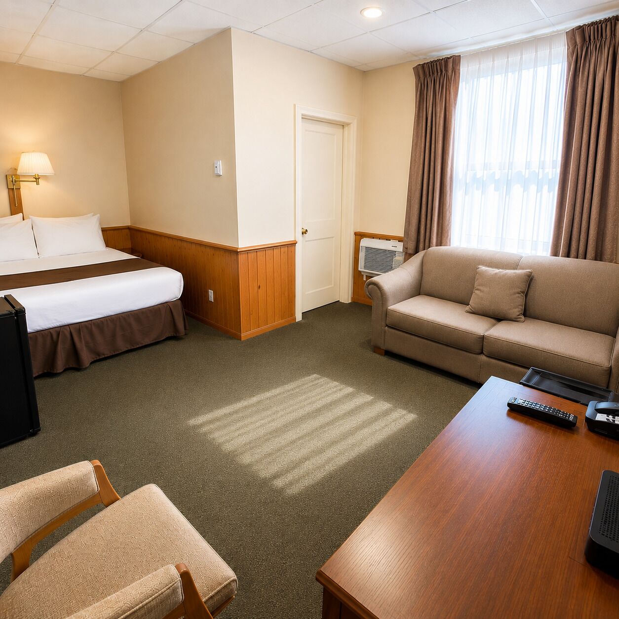 Een hotelkamer met een bed, een bank, een bureau en een stoel.