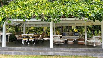 A covered outdoor seating area with wicker furniture and a pergola with climbing plants.