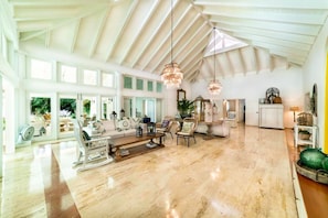 Un salon spacieux avec un plafond haut, de grandes fenêtres et un plancher en bois.