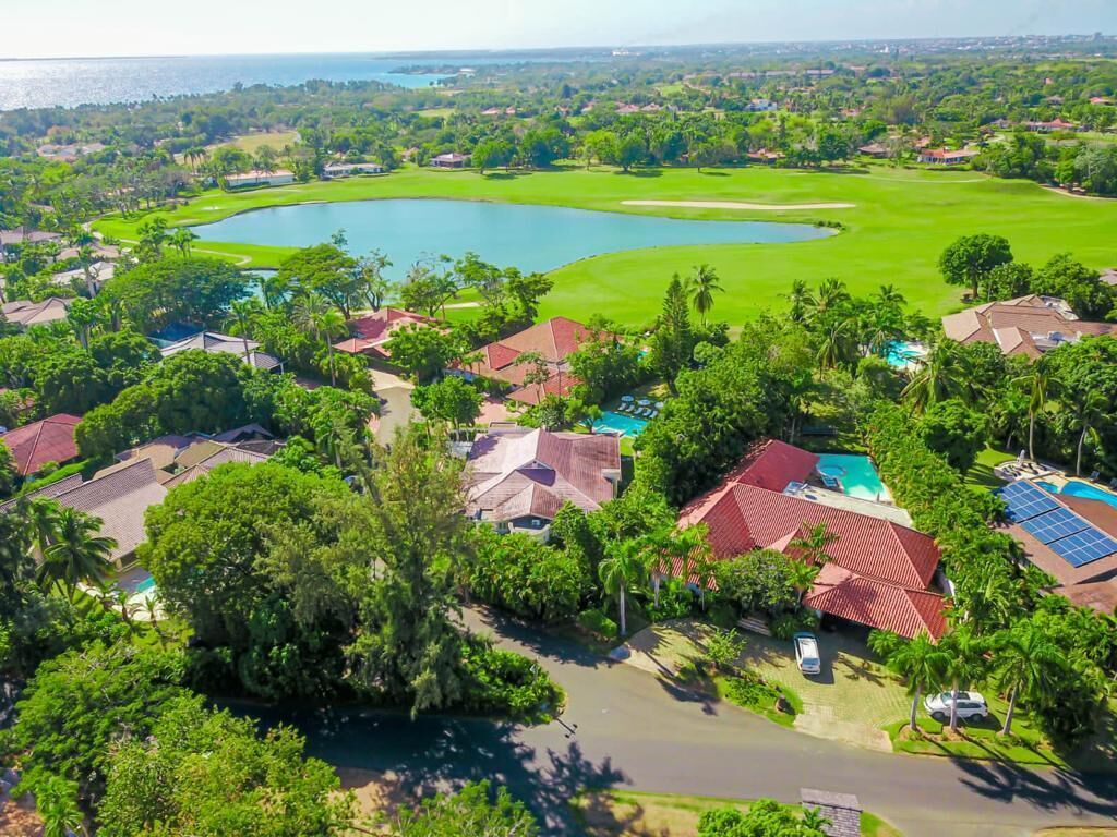An aerial view of a residential area with houses, a golf course, and a body of water.