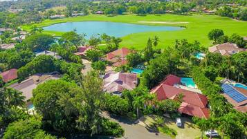 An aerial view of a residential area with houses, a golf course, and a body of water.