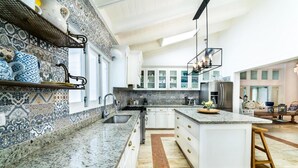Una cocina moderna con una isla central, armarios blancos y un salpicadero estampado.
