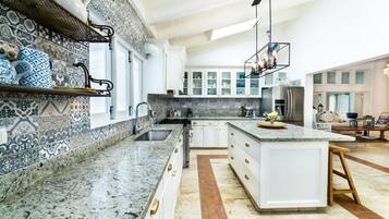 A modern kitchen with a central island, white cabinetry, and patterned backsplash.