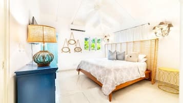 A bedroom with a bed, a blue dresser, a lamp, and a window with curtains.