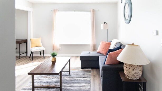 A modern living room with a sofa, a coffee table, a lamp, and a window with curtains.
