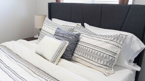 A neatly made bed with patterned pillows and a dark headboard.