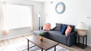A modern living room with a sectional sofa, a wooden coffee table, and a patterned rug.