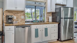 A modern kitchen with white cabinets, a stainless steel refrigerator, and a coffee maker.