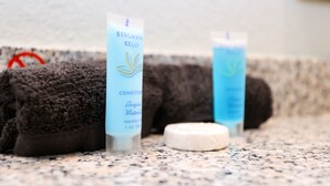 A bathroom with a towel, two bottles of Bergman Kelly conditioner, and a soap bar.