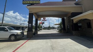 A Regency Inn & Suite with a clear blue sky, a parking lot, and a visible Shell gas station. - Regency Inn and Suites (Humble)