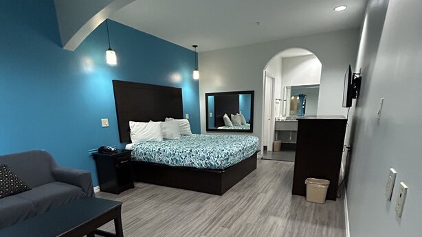A modern bedroom with a bed, a sofa, a desk, and a mirror. - Regency Inn and Suites (Humble)